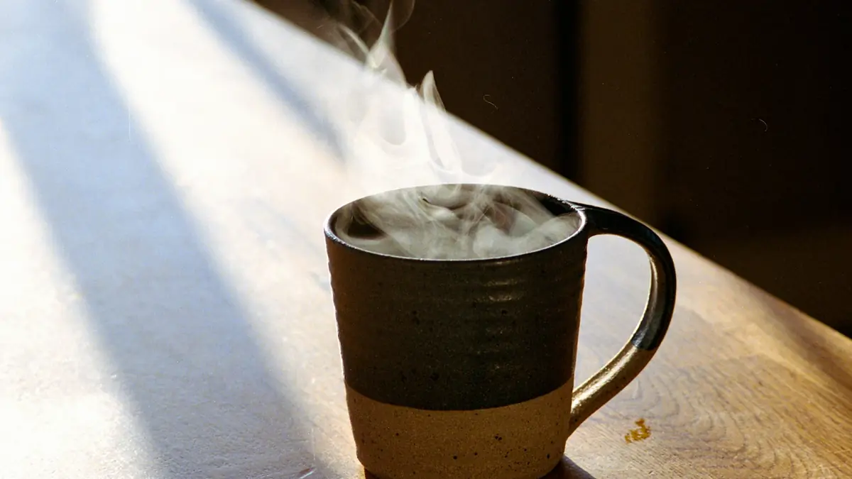 A steaming mug on a sunlit wooden surface
